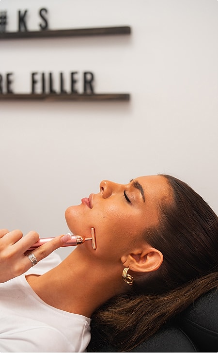 Woman using a facial roller for skincare.